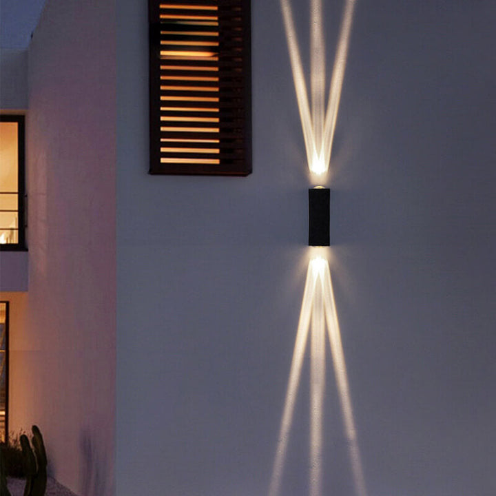 Moderne LED-vegglampe med to lyshoder og aluminiumslinse for utendørs bruk.