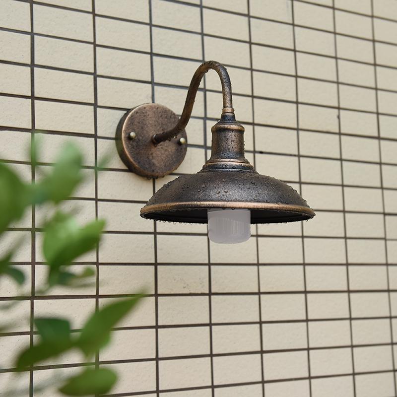 Rund, lokkformet vegglampe med buet jernskjerm og enkeltflammedesign for terrassen