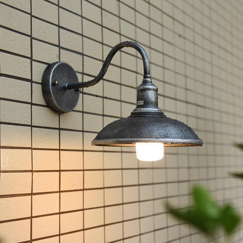 Rund, lokkformet vegglampe med buet jernskjerm og enkeltflammedesign for terrassen