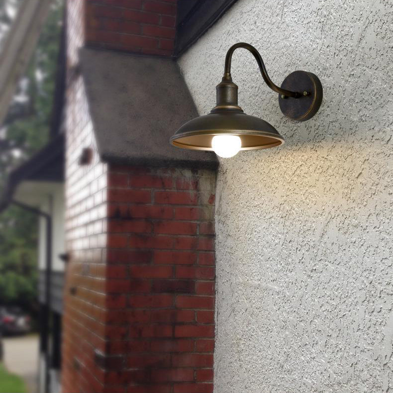 Rund, lokkformet vegglampe med buet jernskjerm og enkeltflammedesign for terrassen