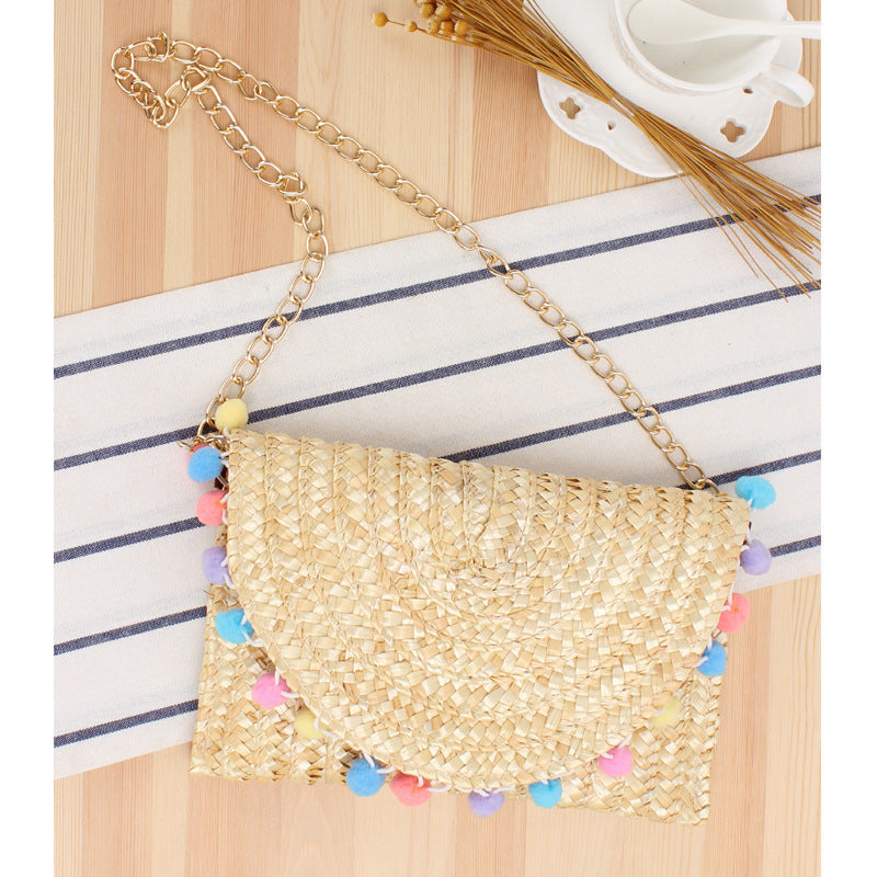 Hand-woven natural material clutch with decorative pom-poms Skanto